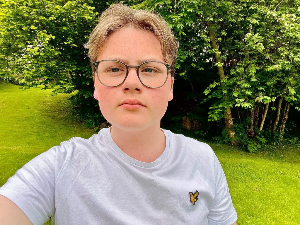 Blond gut med briller foran grøntområde