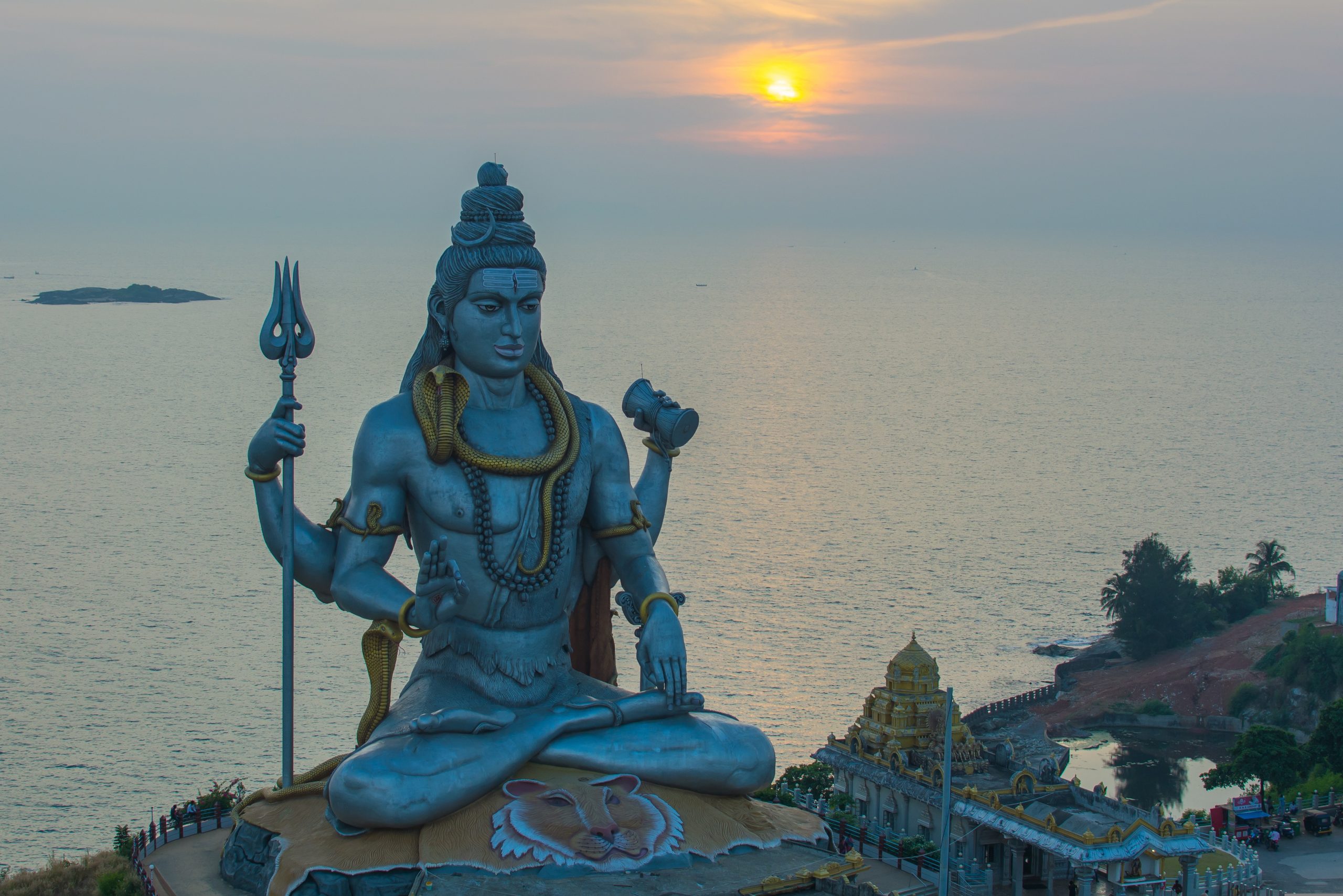 Ein stor statue av guden Shiva foran sjøen.