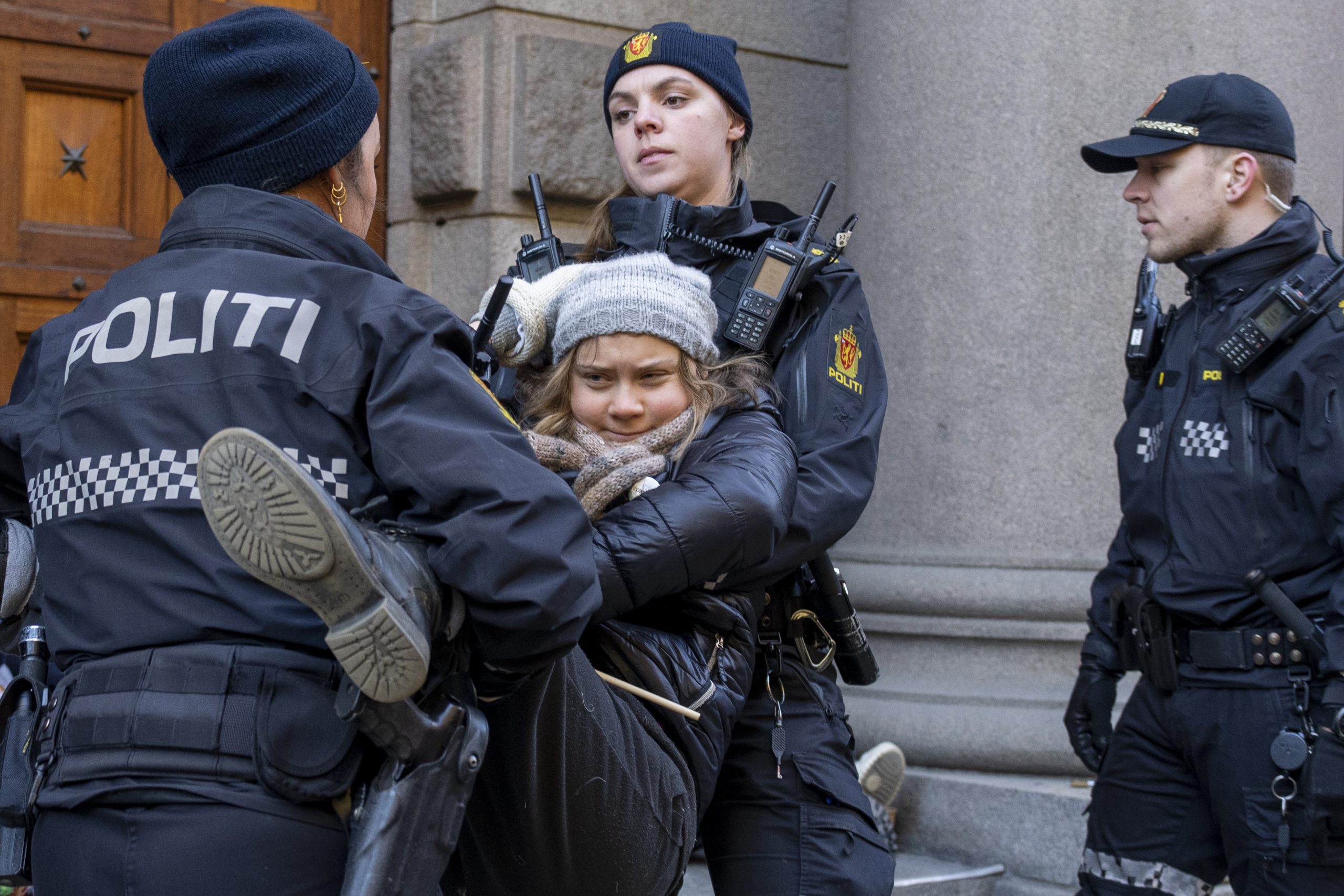 Klimaaktivist Greta Thunberg blir boren av to politifolk, eit politi står på høgre side av skjermen